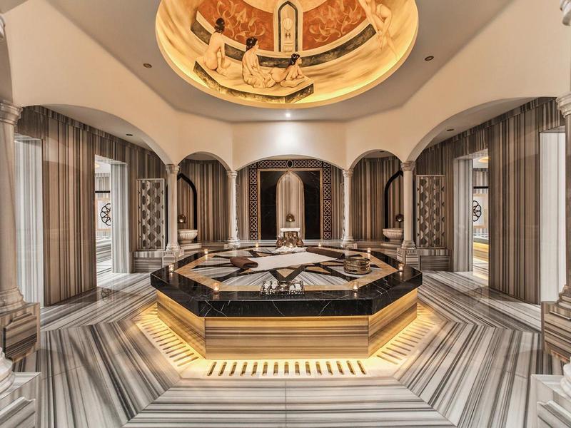 Elegant spa area with central water pool, marble tiles, and artistic ceiling painting.