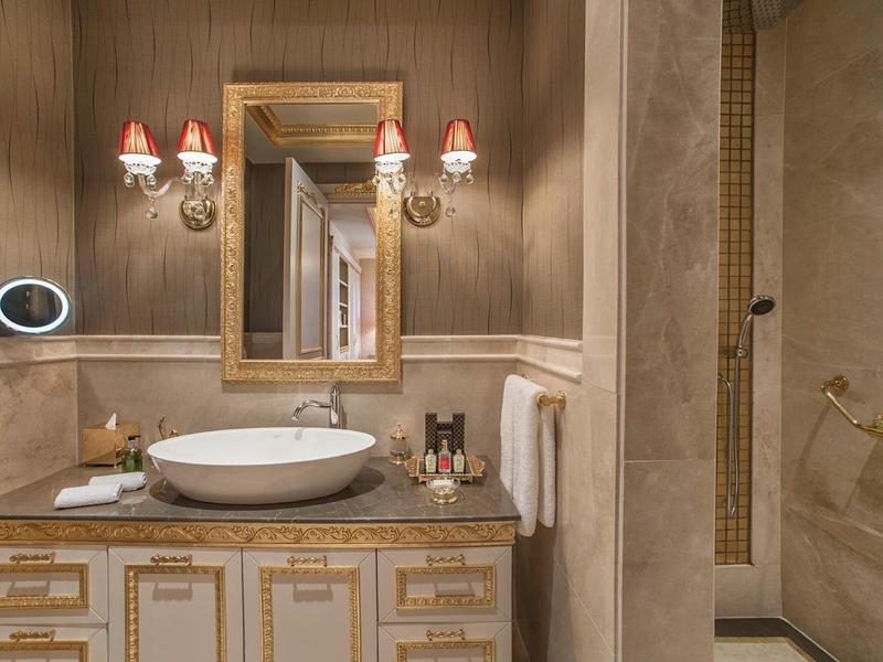 Elegant bathroom with vanity, round sink, gold-framed mirror, and separate shower area.