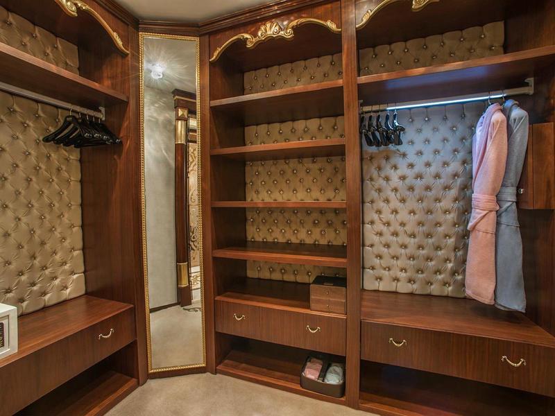 Elegant walk-in closet with wooden shelves, mirror, and bathrobes.