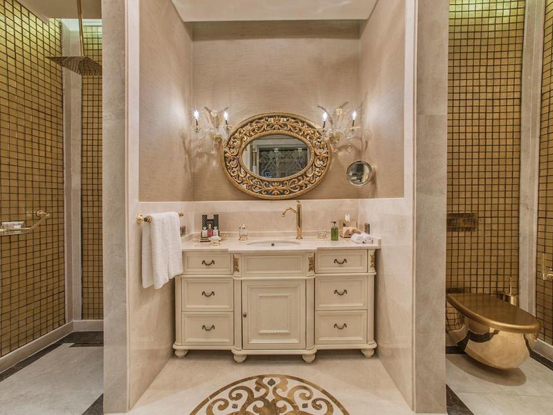 Elegant bathroom with marble vanity, oval mirror, and gold fixtures.