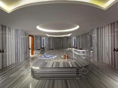 Nowoczesne wnętrze hammamu z szarym marmurem i okrągłym oświetleniem.