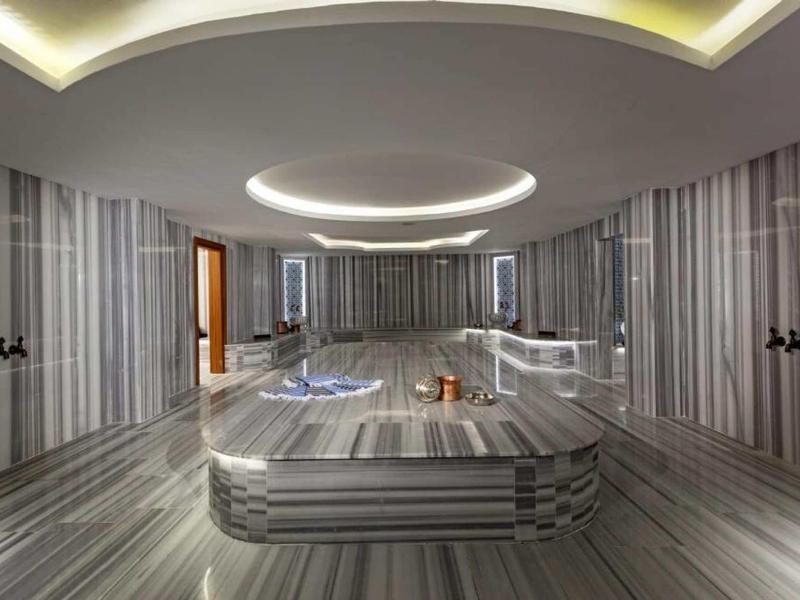 Nowoczesne wnętrze hammamu z szarym marmurem i okrągłym oświetleniem.
