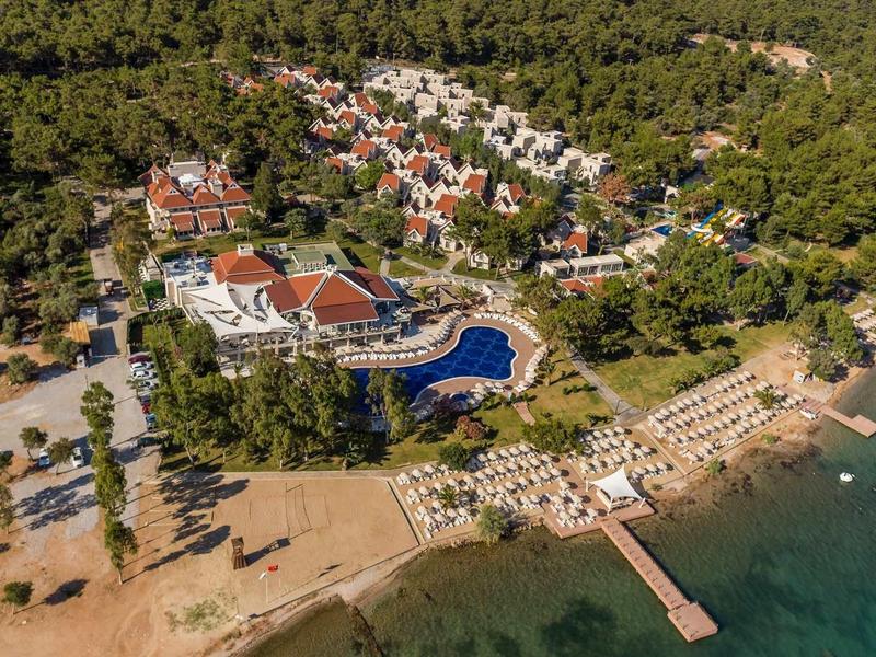 Widok z lotu ptaka na kompleks hotelowy z basenem i plażą nad turkusowym morzem.