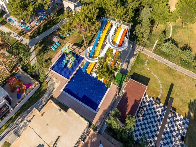 Park wodny z kolorowymi zjeżdżalniami i basenami otoczony zielenią i budynkami.