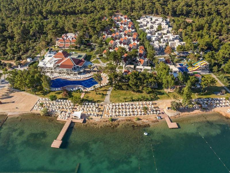 Widok z lotu ptaka na ośrodek z plażami, pomostami i basenami otoczonymi roślinnością.