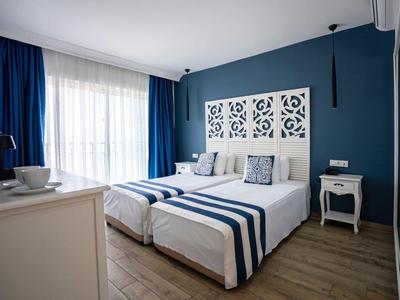 Moderne hotelkamer met tweepersoonsbed, blauwe accenten en licht houten meubels.