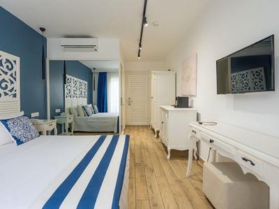 Lichte hotelkamer met tweepersoonsbed, spiegel, tv en houten vloer.