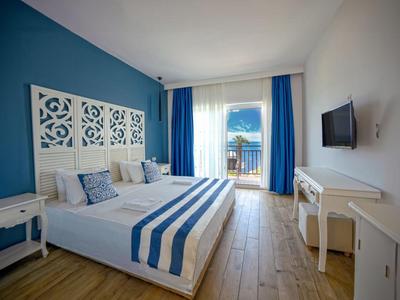 Moderne hotelkamer met tweepersoonsbed, balkon en zeezicht.