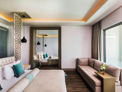Moderne hotelkamer met groot bed, bank en grote spiegel.