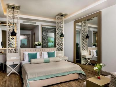 Modern hotelkamer met groot bed, houtkleurige vloer en decoratieve wandelementen.