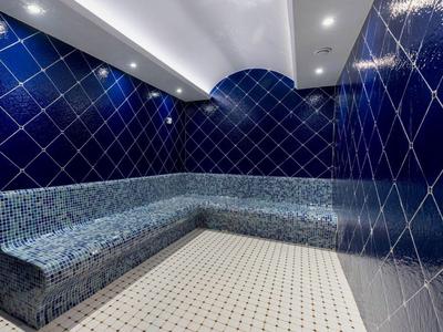 Interieur van een stoomruimte met blauwe tegels en zitbank met mozaïektegels.