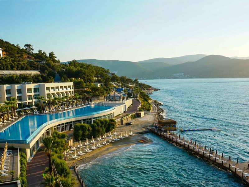 Luxe resort met infinity-zwembad en directe toegang tot de zee bij zonsondergang.