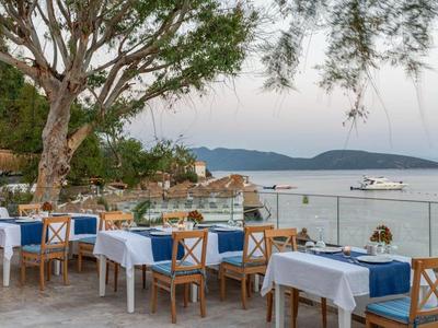 Terrazza del ristorante sull'acqua con vista sul mare e sulle montagne sotto un cielo nuvoloso.
