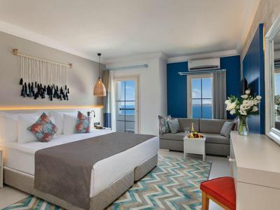 Helles Schlafzimmer mit Doppelbett, pastellfarbenen Wänden, Sofa, Teppich und Schreibtisch.