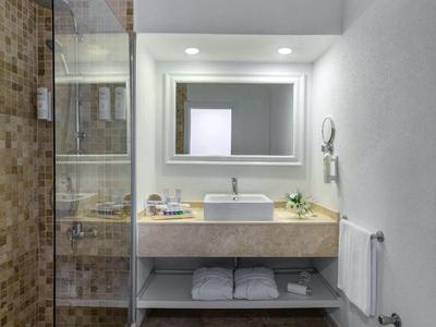 Bagno moderno con doccia in vetro, grande specchio e piano lavabo sospeso.