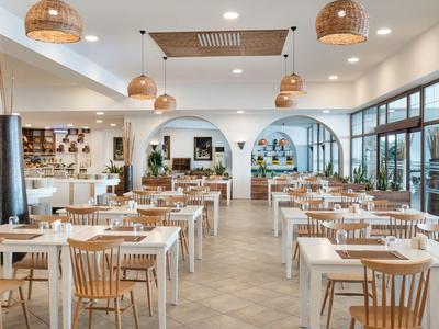 Ristorante luminoso e moderno con mobili in legno e grandi finestre.