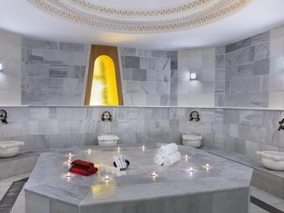 Luksusowy turecki hammam z marmurowymi ścianami, centralną płytą i relaksującymi akcesoriami.