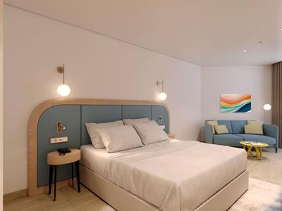 Modern eingerichtetes Hotelzimmer mit Doppelbett, blauer Polsterung und Sofabereich.