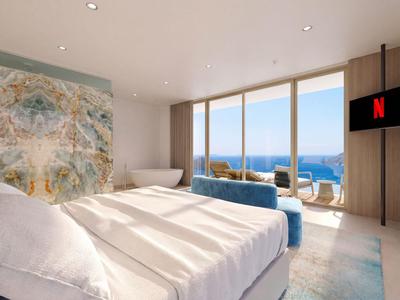 Modernes Hotelzimmer mit Blick auf das Meer, großer Bett und Sitzecke neben bodentiefen Fenstern.
