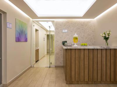 Hotelreceptie met houten balie, bloemen en moderne verlichting.