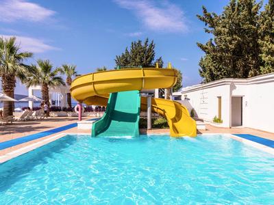 Pool mit Wasserrutschen und Palmen unter blauem Himmel in einem Ferienresort