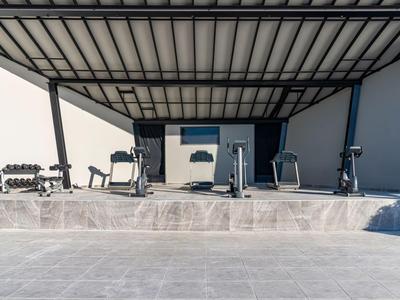 Überdachter Fitnessbereich mit Laufbändern und Hanteln auf einer Terrasse.