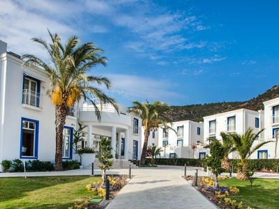 Witte hotelgebouwen met palmbomen en een heldere blauwe lucht.