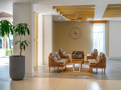 Moderne hotel lobby zithoek met houten stoelen, kussens, salontafel en een potplant.