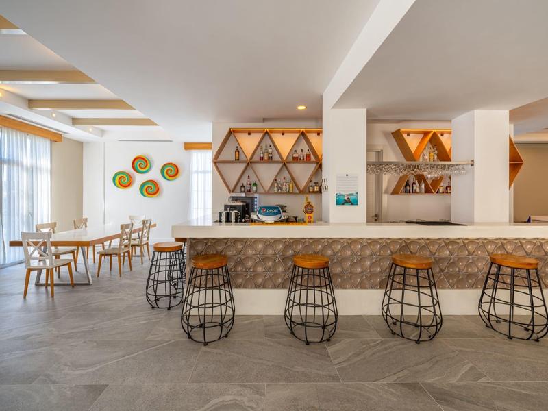 Moderne hotel loungebalie met barkrukken en tafels in een lichte, open ruimte.