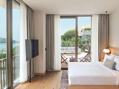 Modernes Hotelzimmer mit Doppelbett, TV und Balkon mit Meerblick.