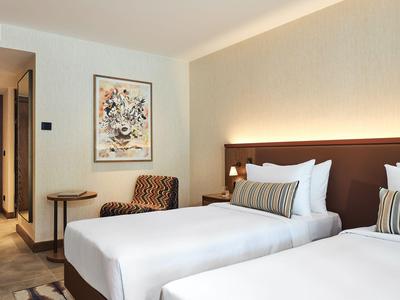 Modern eingerichtetes Hotelzimmer mit zwei Einzelbetten, passend für eine entspannte Reise.