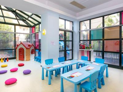 Colorful children's playroom with small tables, chairs, and cushions in a bright room.