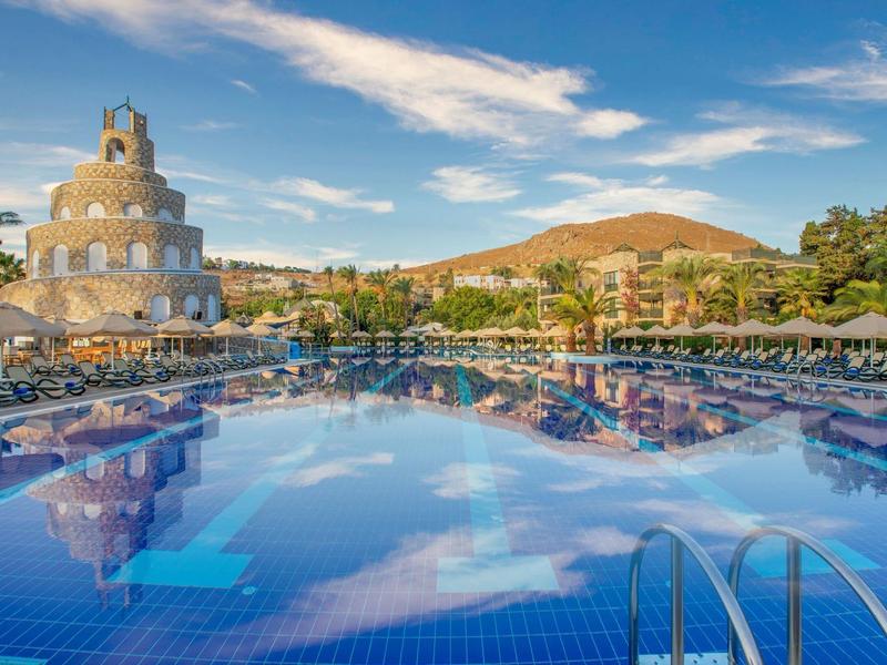 Large hotel pool with umbrellas and loungers under a blue sky