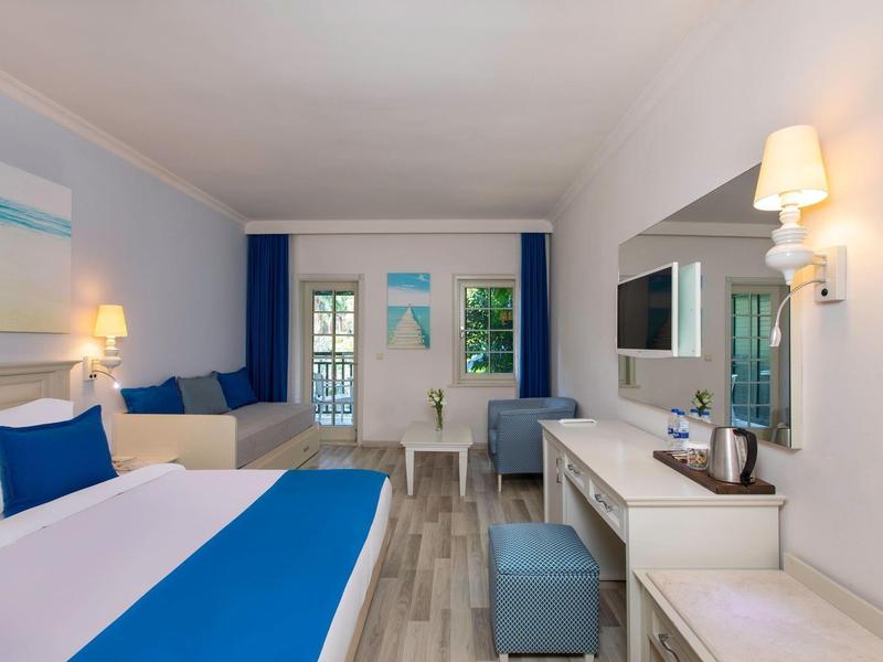 Modern hotel room with blue and white decor and a desk area.