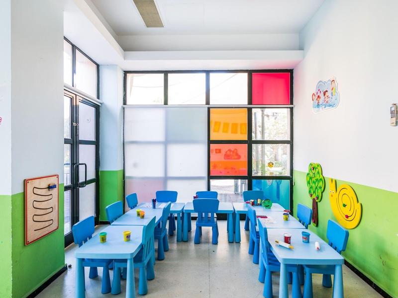 Colorful children's playroom with blue tables and chairs, decorated with cheerful wall art.