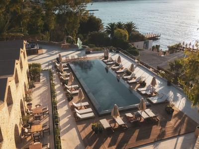 Area piscina di lusso con lettini e vista sul mare al tramonto.