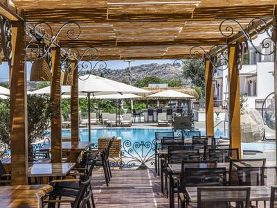 Terrazza coperta con tavoli e sedie accanto a una piscina in un hotel.