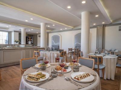 Ristorante luminoso e elegante con tavoli rotondi apparecchiati e pavimento in legno.