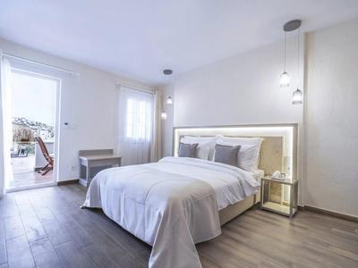 Camera moderna con letto matrimoniale, tende chiare e accesso a un balcone con vista esterna.