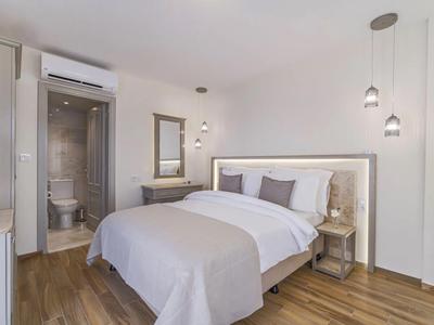 Camera d'hotel moderna con letto matrimoniale, comodini, specchio e bagno con toilette.