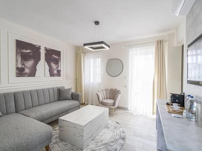 Soggiorno luminoso con divano grigio, tavolino in marmo e decorazioni murali.