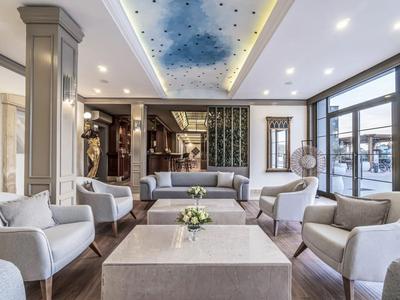 Moderna hall d'hotel con comode poltrone, grande tavolo e illuminazione elegante sul soffitto.