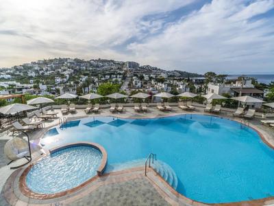 Grande piscina con vista sulla città e sul mare sotto un cielo nuvoloso.