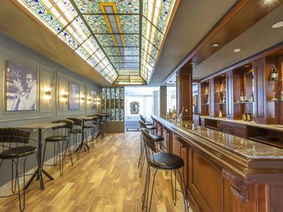 Area bar di hotel moderna con bancone in legno, posti a sedere e tetto in vetro.