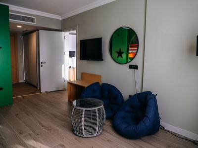 Gemütliche Sitzecke mit blauen Kissen, kleinem Tisch und rundem Spiegel im modernen Hotelzimmer.