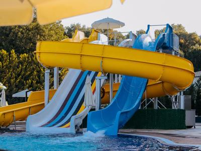 Colorful water slides with yellow and blue designs next to a pool in an outdoor water park setting.