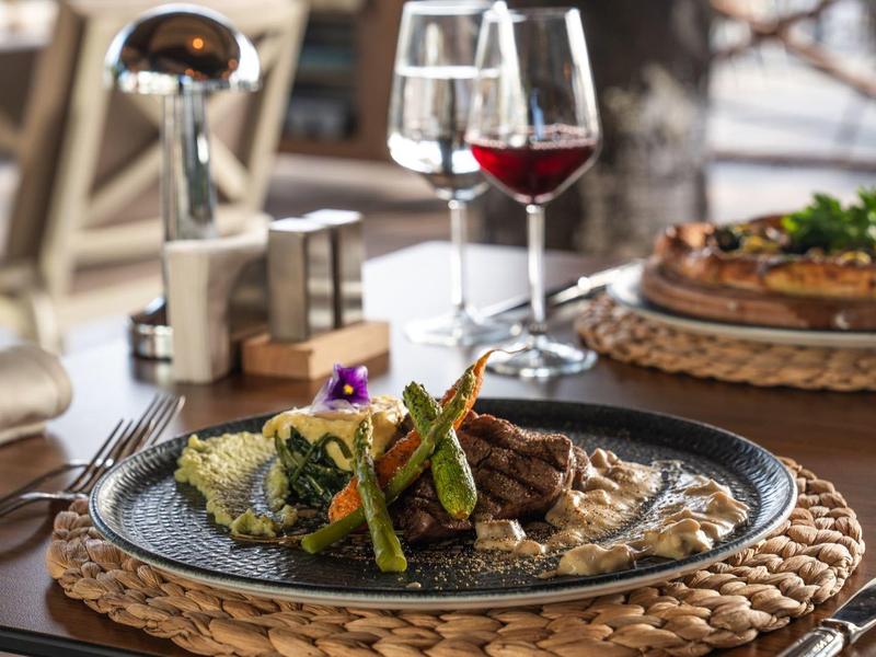 Gourmet posiłek z mięsem, warzywami i czerwonym winem na drewnianym stole.