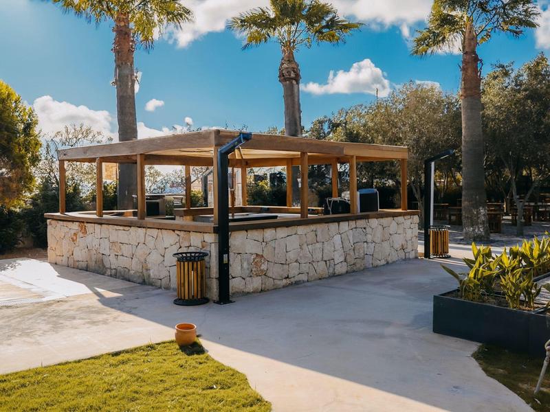 Zewnętrzny taras z kamienia z pergolą otoczony palmami.