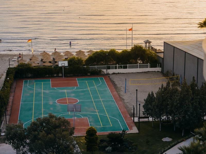 Boisko sportowe obok plaży z widokiem na morze o zachodzie słońca.