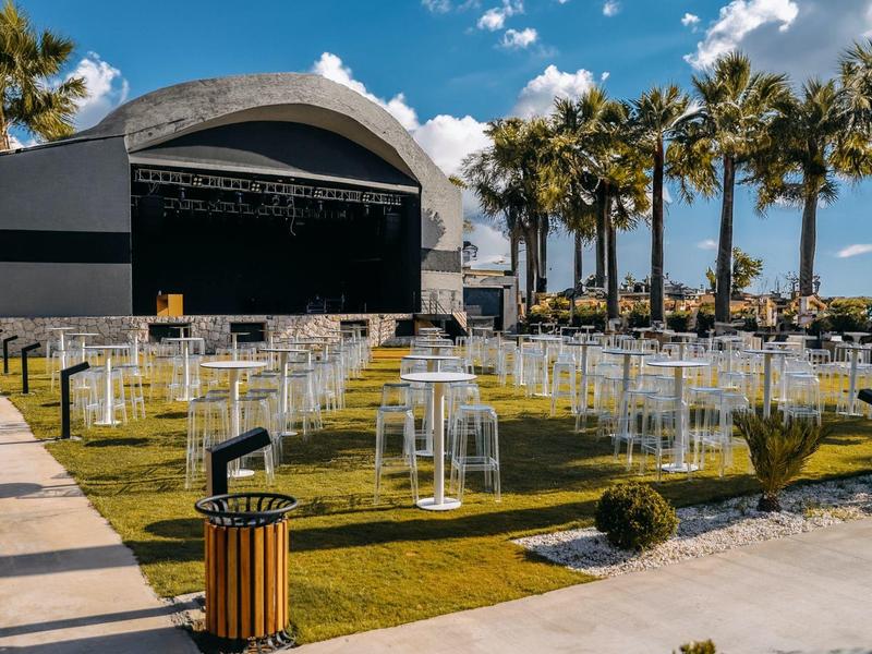 Nowoczesny pokój hotelowy z podwójnym łóżkiem, zielonymi poduszkami i lampką na stoliku nocnym.